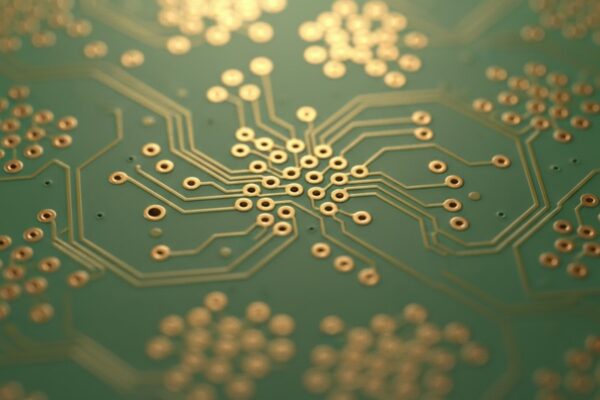 Life After RoHS: Navigating the End of Exemptions for Leaded BGAs An abstract macro photograph of a green printed circuit board, with a very shallow depth of field creating a soft, blurred background of geometric shapes and copper traces.