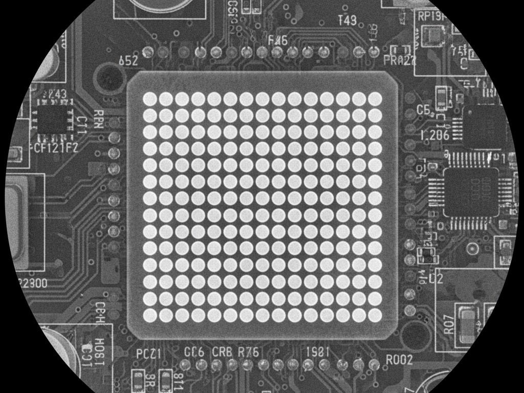 An X-ray image of a Ball Grid Array (BGA) chip, revealing the perfectly aligned grid of circular solder balls that connect it to the circuit board underneath.