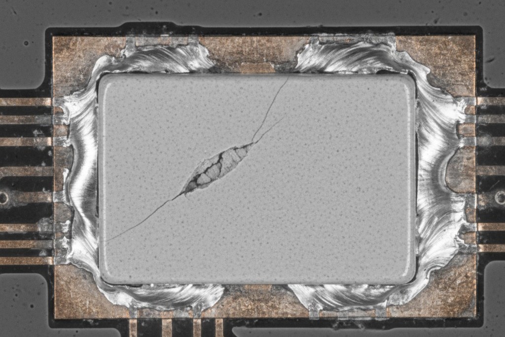 A highly magnified scanning electron microscope image revealing a micro-crack in a surface-mount ceramic capacitor.