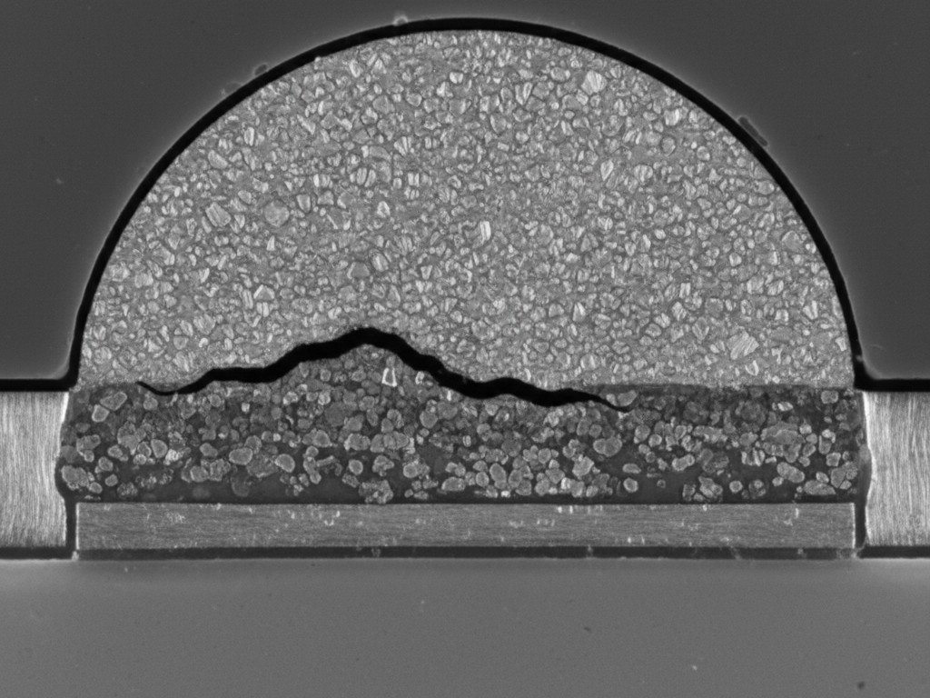 A microscopic, cross-section view of a BGA solder joint showing a dark crack propagating through the brittle intermetallic layer, demonstrating a common failure point.