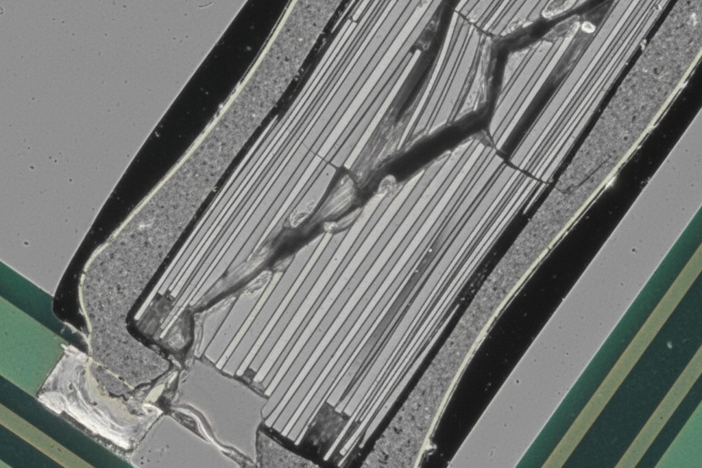 Micrografía de una grieta en un capacitor Chevron Una sección transversal microscópica de un capacitor cerámico muestra una grieta de 45 grados que se propaga diagonalmente desde la base del componente hasta su cuerpo.