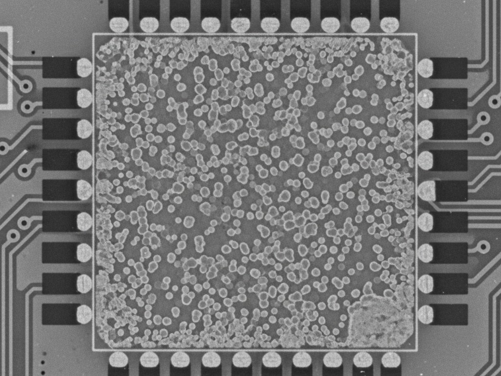 Un rayos X de una almohadilla térmica grande, cuadrada, en una placa de circuito. La almohadilla está llena de numerosos vacíos pequeños, creando un patrón de panal de miel de soldadura.