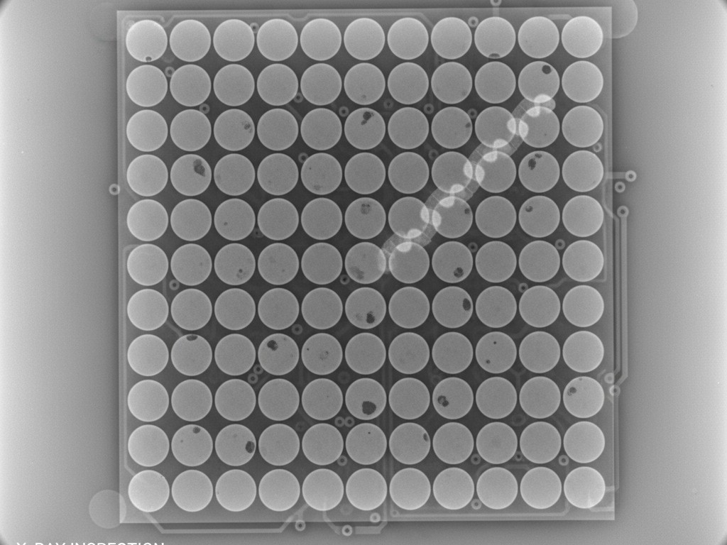 A grayscale X-ray image of a BGA component on a circuit board, showing the perfectly spherical and aligned solder balls underneath.