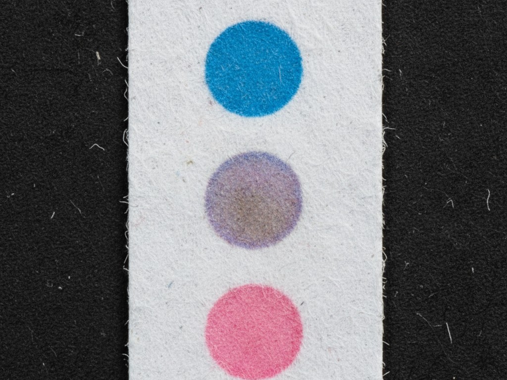 Крупный план карты индикатора влажности Макросъемка бумажной карты индикатора влажности с тремя круглыми точками, одна из которых меняет цвет на грязно-лавандовый.