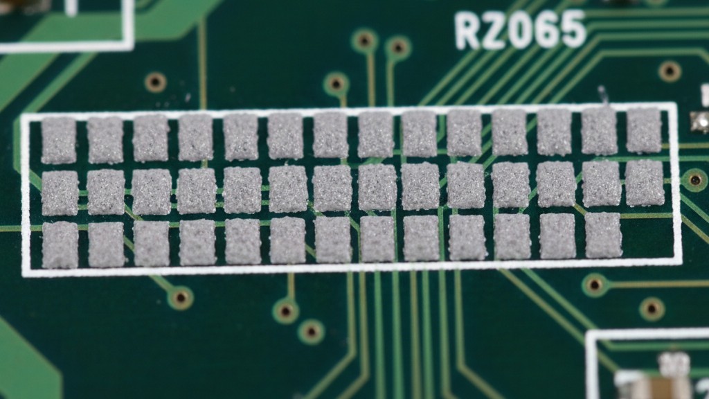 Window-pane solder paste pattern A close-up of gray solder paste printed on a circuit board's linear ground pads in a segmented, block-like pattern.